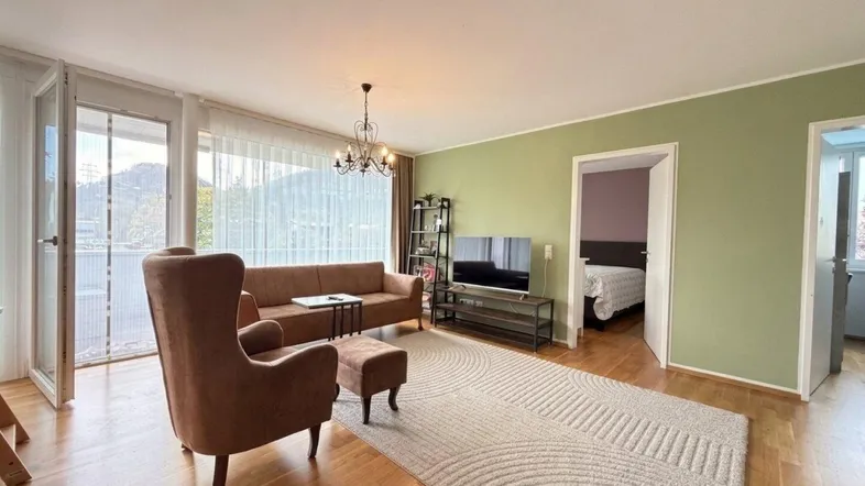 Helles Wohnzimmer mit Parkettboden, gemütlicher Sitzecke und Zugang zum Balkon.