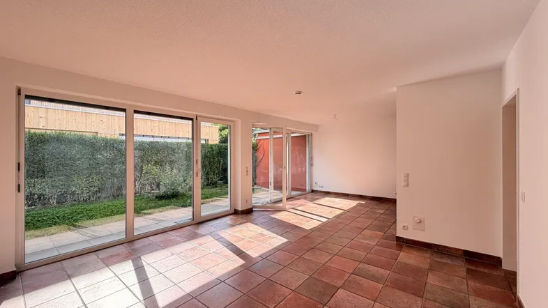 Helles Wohnzimmer mit Terracottaboden und großen Schiebetüren zum Gartenbereich.