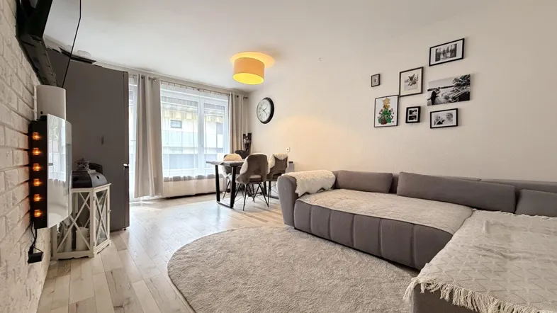 Heller Wohn-Essbereich mit modernem Sofa, Esstisch und hellem Holzboden.
