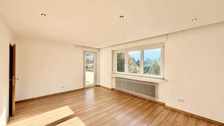 Helles Zimmer mit Holzboden, großen Fenstern und Zugang zu einem Balkon, bietet viel Tageslicht.