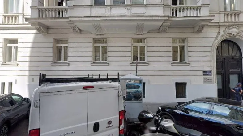 Historische Fassade eines Gebäudes mit mehreren Balkonen und einem großen, gewölbten Eingangsbereich.
