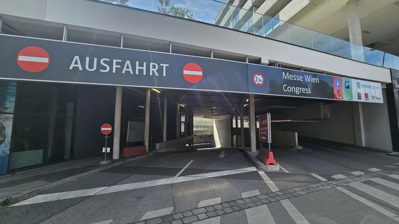 Einfahrt zur Tiefgarage mit Beschilderung und Höhenbegrenzung, umgeben von moderner Architektur.