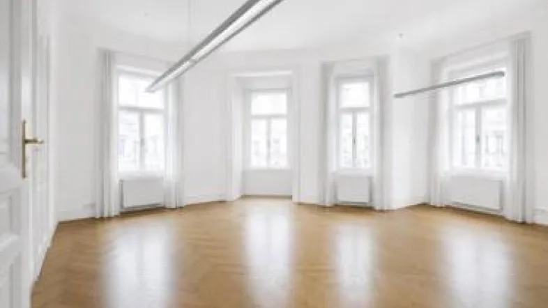 Heller, leerer Raum mit Fischgrätparkett und großen Fenstern, ideal für Büro oder Wohnen.