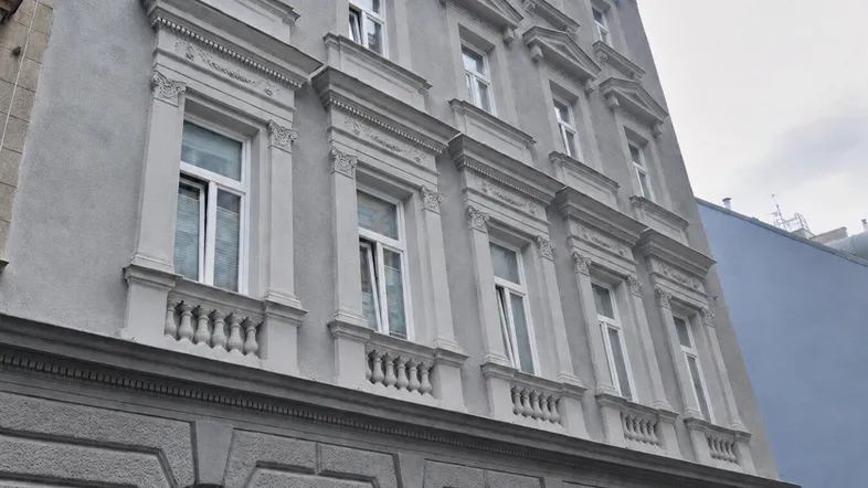Historische Fassade eines Altbaus mit aufwendigen Verzierungen und klassischen Fenstern.