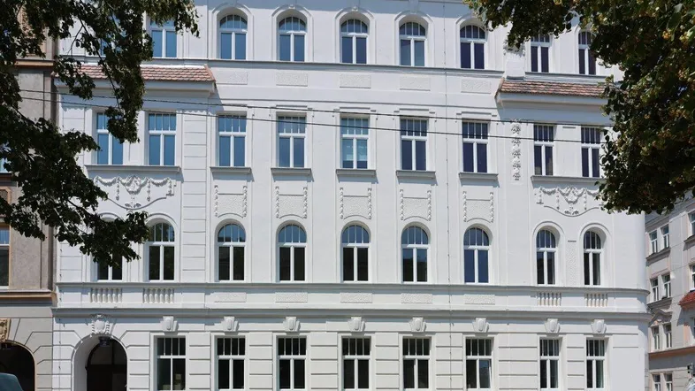 Die frisch renovierte Fassade eines klassischen Wiener Altbaus mit modernen Dachgeschossfenstern.
