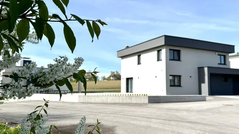 Außenansicht des Hauses mit blühenden Bäumen im Vordergrund und ländlicher Umgebung.