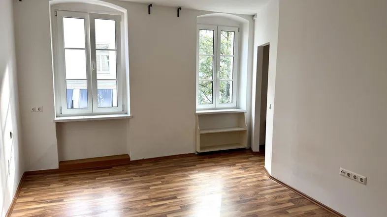 Heller Raum mit Laminatboden und zwei Fenstern, ideal als Wohn- oder Schlafzimmer nutzbar.