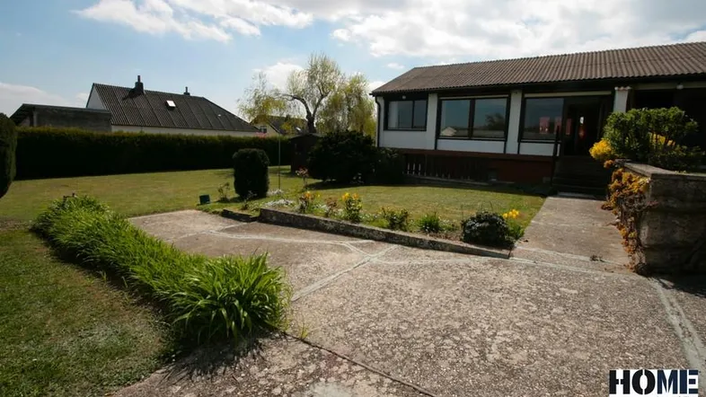 Vorderansicht des Hauses mit gepflegtem Rasen, Blumenbeeten und einem gepflasterten Weg.