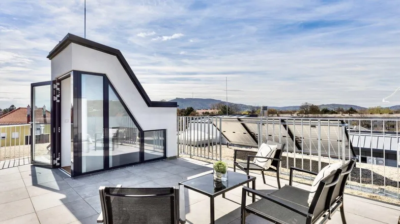 Große Dachterrasse mit modernen Gartenmöbeln und weitem Blick über die Umgebung.