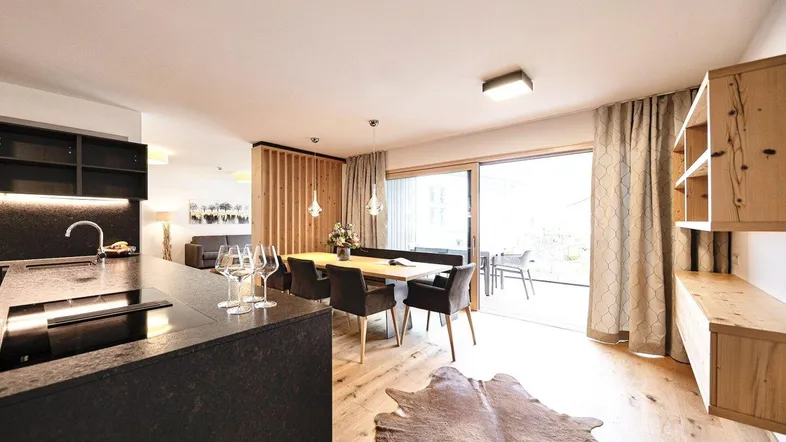 Offener Wohn- und Essbereich mit moderner Küche, Holzboden und Zugang zur Terrasse.