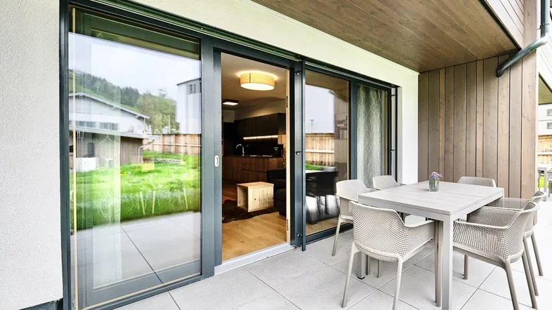 Moderne Terrasse mit Essbereich und Blick in den offenen Wohn- und Küchenbereich des Anwesens.