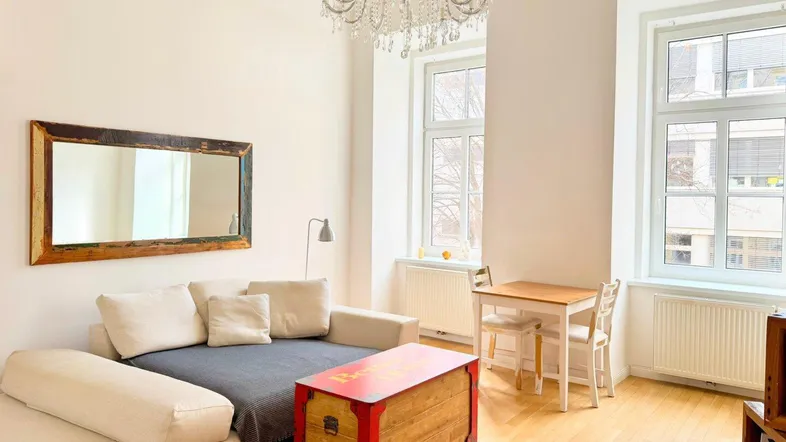 Helles Wohnzimmer mit Parkettboden, Kronleuchter und einem dekorativen Couchtisch.
