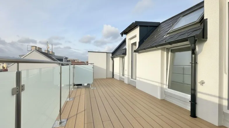 Geräumige Dachterrasse mit Holzboden und Glasgeländer, ideal für Entspannung im Freien.