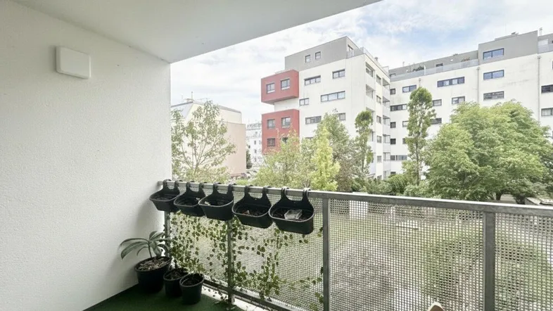 Geräumiger Balkon mit Kunstrasen und Blick auf die umliegenden Wohngebäude.
