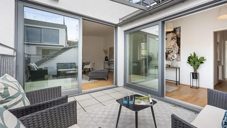 Geräumige Dachterrasse mit bequemen Sitzgelegenheiten und direktem Zugang zum hellen Wohnbereich.