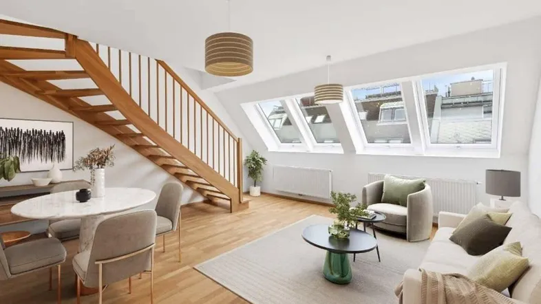 Helles, möbliertes Dachgeschoss-Wohnzimmer mit Essbereich, Holztreppe und großen Dachfenstern.