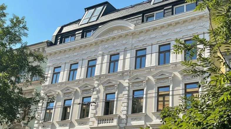 Historische Fassade eines Altbaus mit reich verzierten Details und Dachgauben.