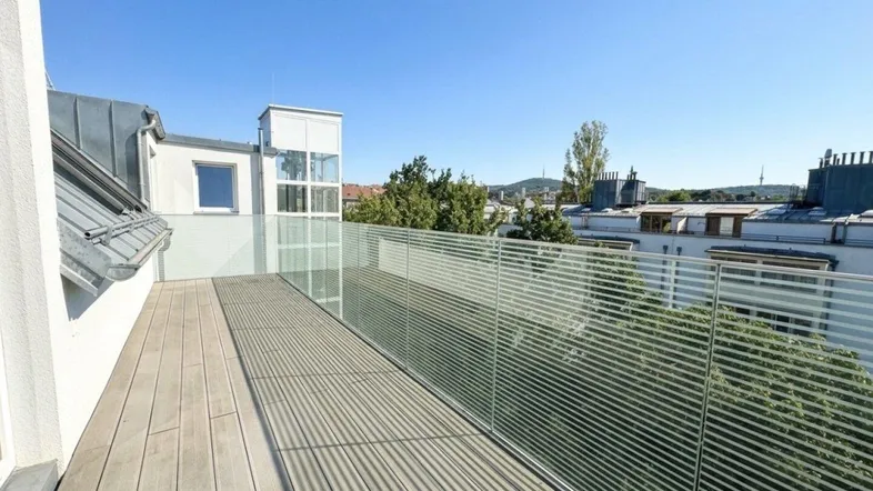 Geräumige Dachterrasse mit Holzboden und Glasgeländer, bietet einen weiten Blick über die Stadt.