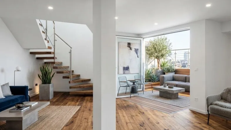Helles Wohnzimmer mit Holzboden, moderner Treppe und Zugang zu einer Dachterrasse.