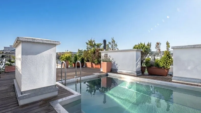 Exklusive Dachterrasse mit integriertem Pool und Holzdeck unter blauem Himmel.