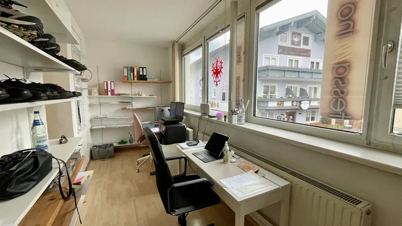 Helles Büro mit mehreren Arbeitsplätzen, Regalen voller Schuhe und Blick auf die Straße und gegenüberliegende Gebäude.