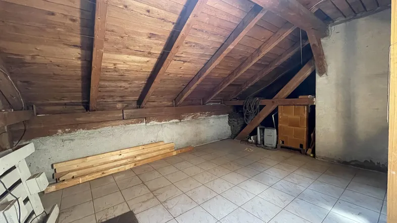 Unfertiger Dachboden mit sichtbaren Holzbalken und Fliesenboden, bereit für Ausbau.