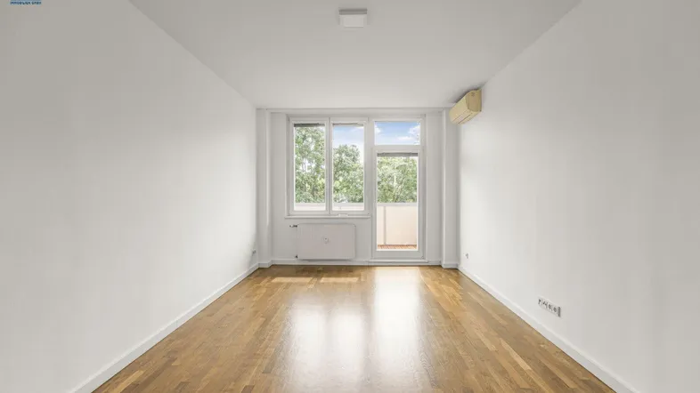 Geräumiges Zimmer mit Parkettboden und direktem Balkonzugang, bietet viel Tageslicht.