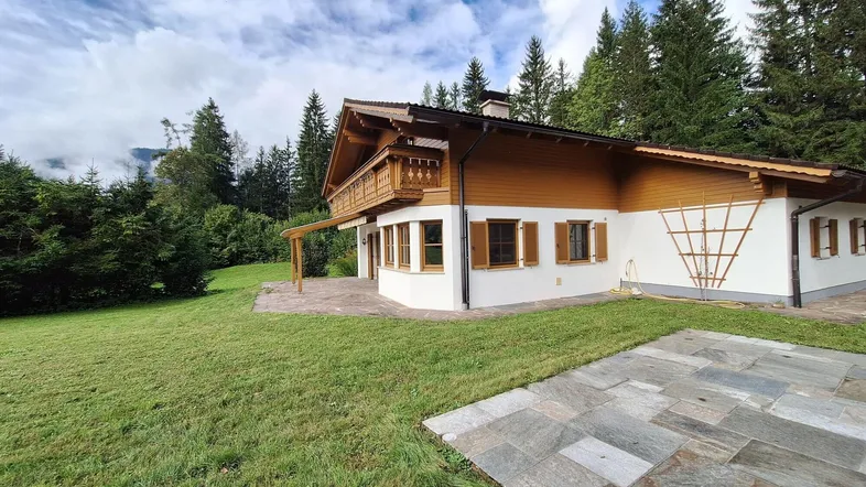 Traditionelles Haus im alpenländischen Stil mit großem Garten, Terrasse und Bergblick.