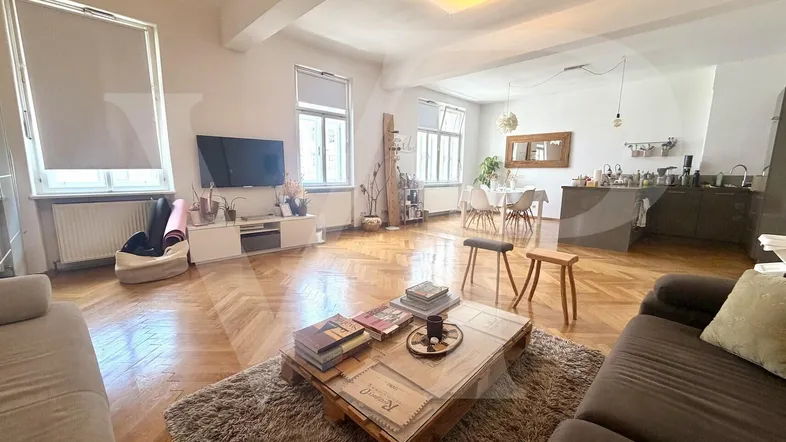 Helles, offenes Wohnzimmer mit Fischgrätparkett und integrierter Küche, ideal für geselliges Beisammensein.
