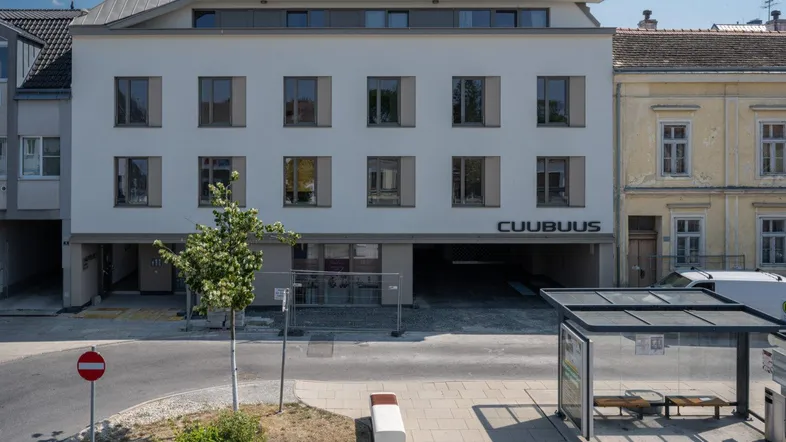 Neubau mit heller Fassade, großen Fenstern und integrierter Tiefgaragenzufahrt an einer städtischen Straße.