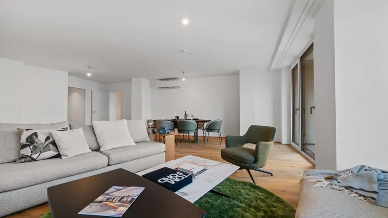 Geräumiger, offener Wohn- und Essbereich mit modernem Design, Holzboden und Zugang zum Balkon.