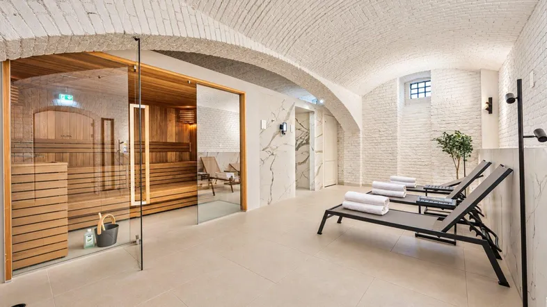 Moderner Wellnessbereich mit Sauna, Liegestühlen und gewölbter Ziegeldecke.