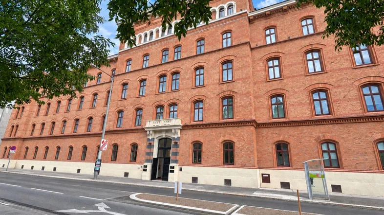 Historisches Backsteingebäude mit vielen Fenstern und klassischer Architektur an einer städtischen Straße.