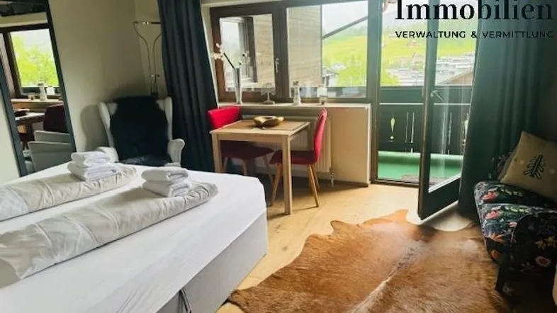 Gemütliches Schlafzimmer mit Doppelbett, kleinem Essbereich und Zugang zum Balkon mit Bergblick.