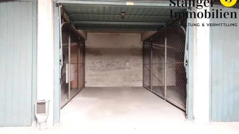 Blick in eine Tiefgarage mit offenen Garagentoren zu den einzelnen Stellplätzen und Betonwänden.