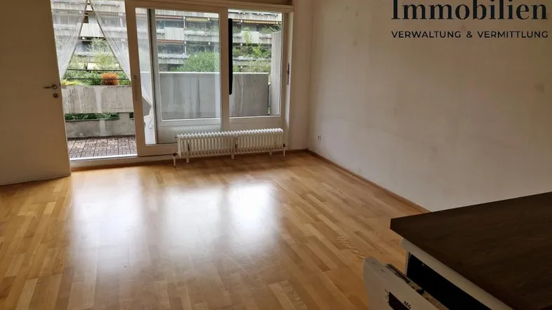 Helles Wohnzimmer mit Parkettboden und Zugang zu einem Balkon, ideal für entspannte Stunden.