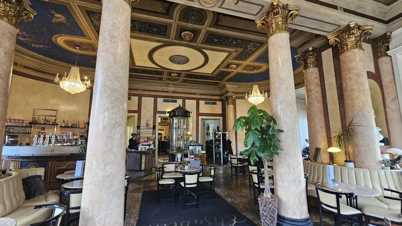 Elegantes Restaurant mit hohen Säulen, kunstvoller Deckenmalerei und gemütlichen Sitzbereichen.
