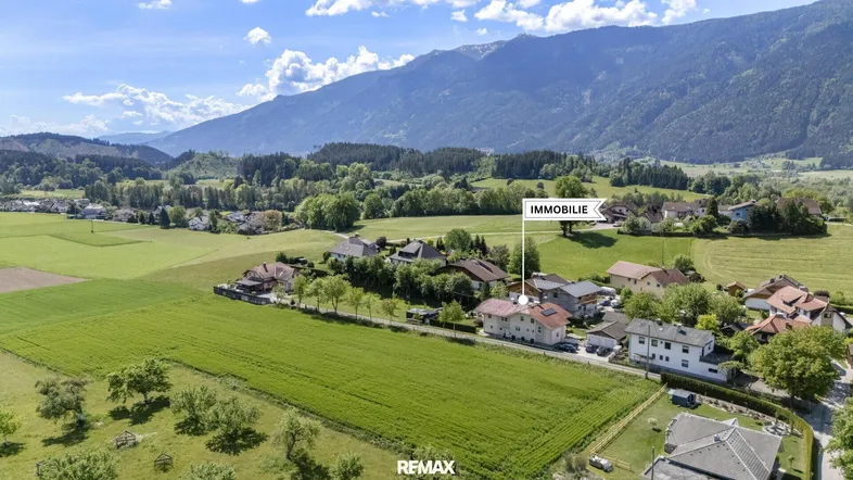 Luftaufnahme der Immobilie in ländlicher Umgebung mit Bergen im Hintergrund und grünen Feldern.