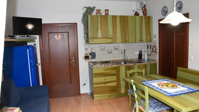 Gemütlicher Wohn- und Essbereich mit rustikaler Holzküche und blauem Retro-Kühlschrank.