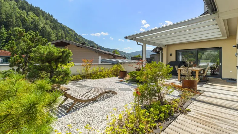 Große Sonnenterrasse mit Holzboden, Gartenbereich und Bergblick, ideal zum Entspannen im Freien.