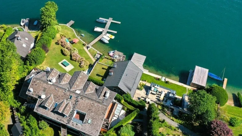 Panoramische Luftaufnahme des luxuriösen Anwesens am Seeufer mit weitläufigen Gärten und Bootsstegen.