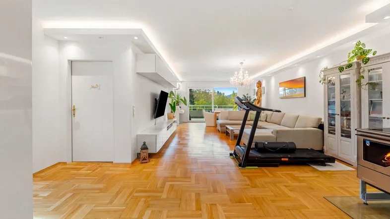 Geräumiges Wohnzimmer mit Parkettboden, moderner Einrichtung und indirekter Beleuchtung.