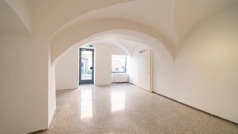 Leerer Raum mit Gewölbedecke und Terrazzoboden, ideal für gewerbliche Nutzung oder als Mehrzweckraum.