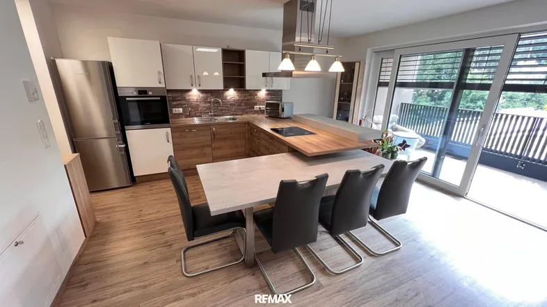 Moderne offene Küche mit Holzelementen, Essbereich und Zugang zum Balkon.