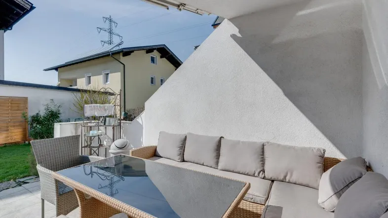 Gemütliche Terrasse mit Rattanmöbeln und Blick auf die Umgebung.