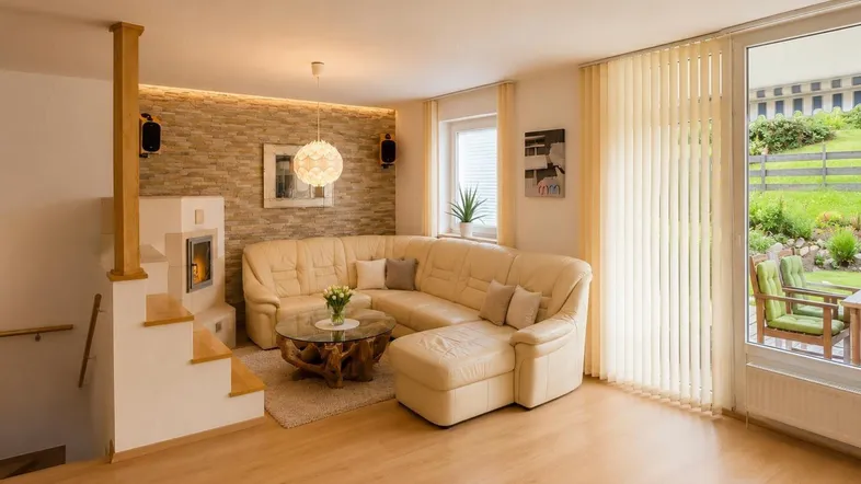 Gemütliches Wohnzimmer mit Ecksofa, Kamin und Zugang zum Gartenbereich.