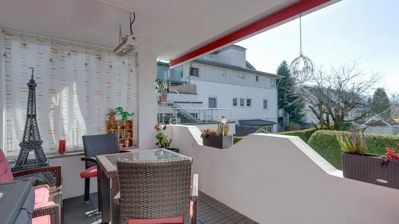Möblierter Balkon mit Sitzgelegenheiten und Blick auf die umliegende Landschaft und Berge.