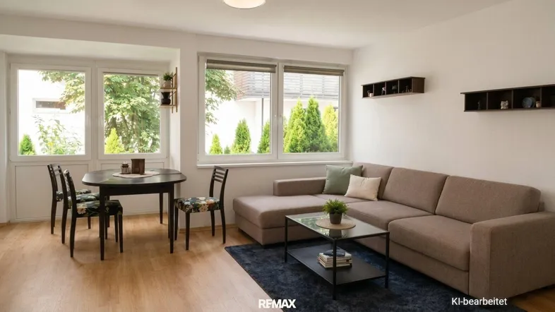 Helles Wohn- und Esszimmer mit Parkettboden, bequemer Couch und Blick ins Grüne.