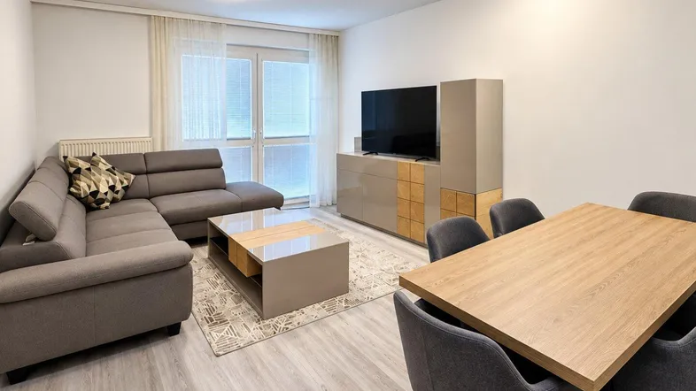 Moderner Wohn- und Essbereich mit hellem Laminatboden, bequemer Couch und Esstisch für sechs Personen.