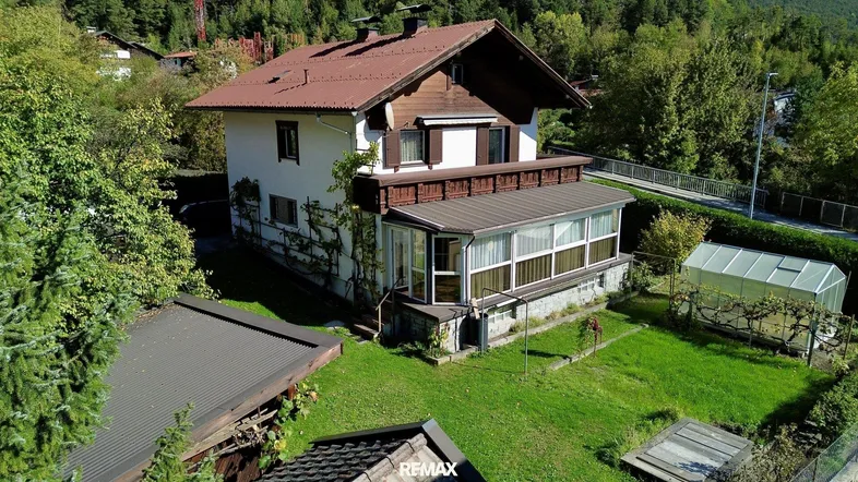 Luftaufnahme des Einfamilienhauses mit großem Garten, Gewächshaus und umgebender Natur.